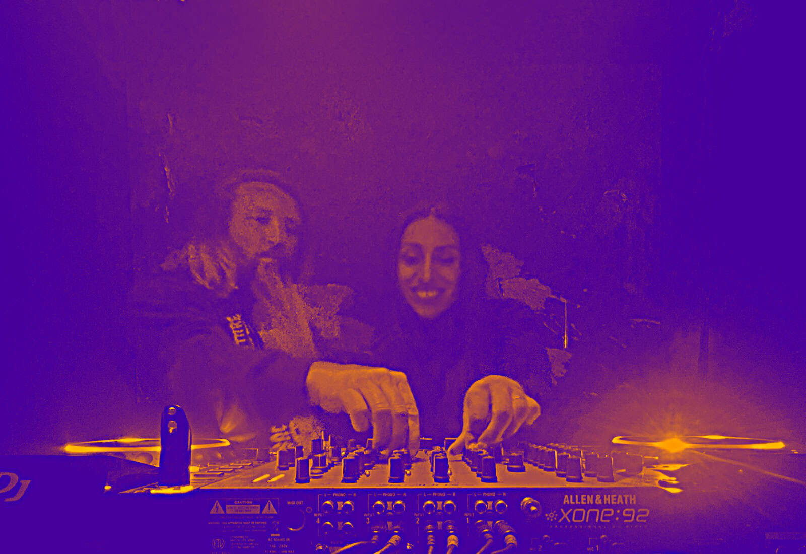 DJ mixing music at BudenMusik event with two smiling women.