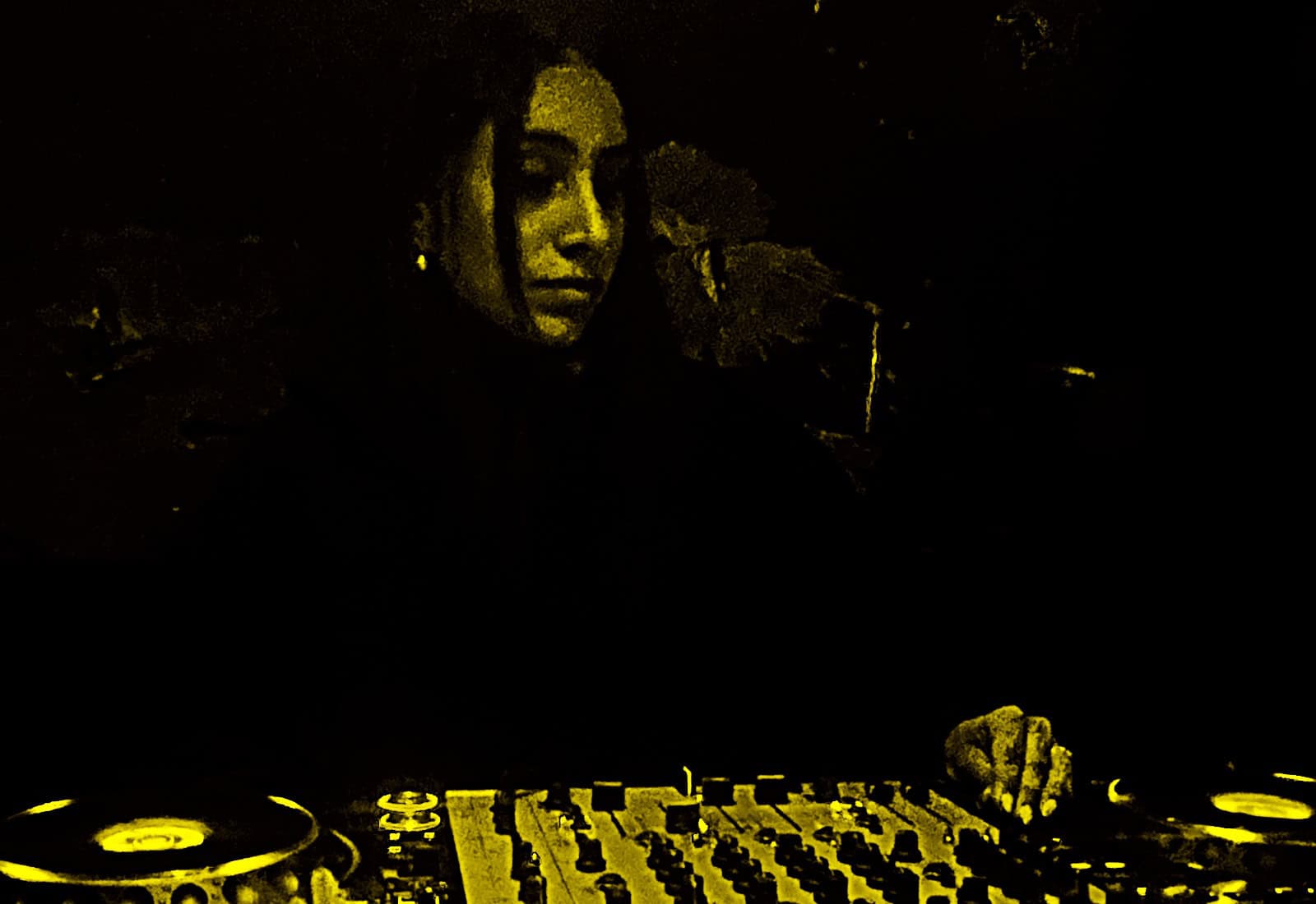 DJ mixing music at night with turntables and mixer.